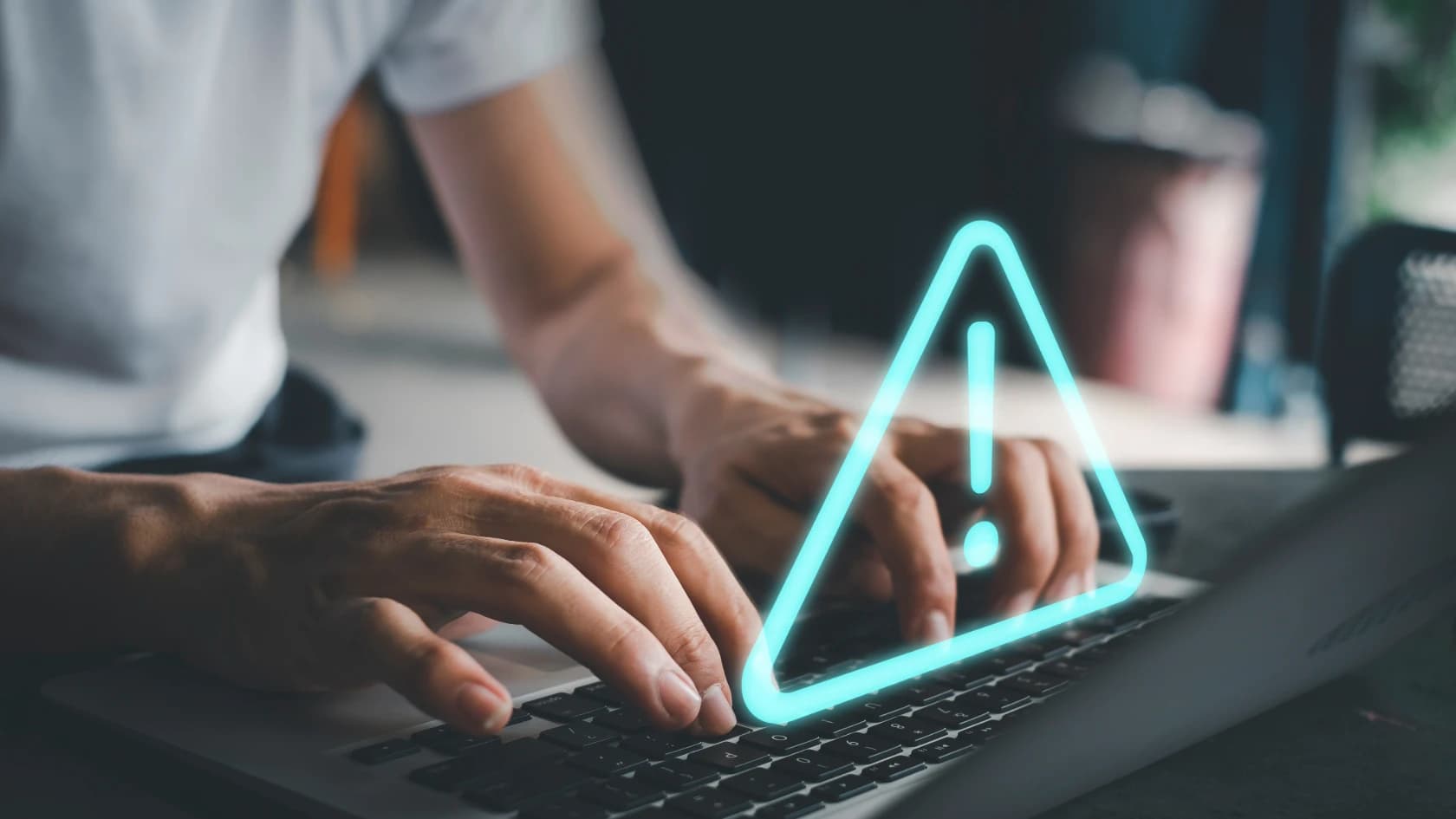 노트북 키보드를 타이핑하는 손 위에 경고 아이콘이 표시된 장면, 홈페이지 유지보수와 추가 비용 리스크를 상징하는 이미지