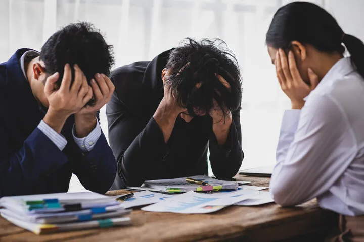 회의실에서 머리를 감싸며 후회하는 사람들